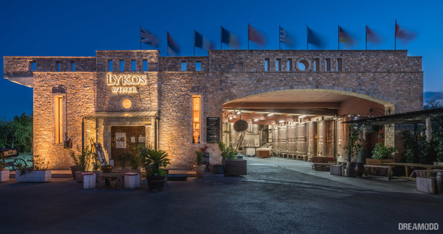 front view of the illuminated building that says 'LYKOSWINERY' in upper part of the wall by night